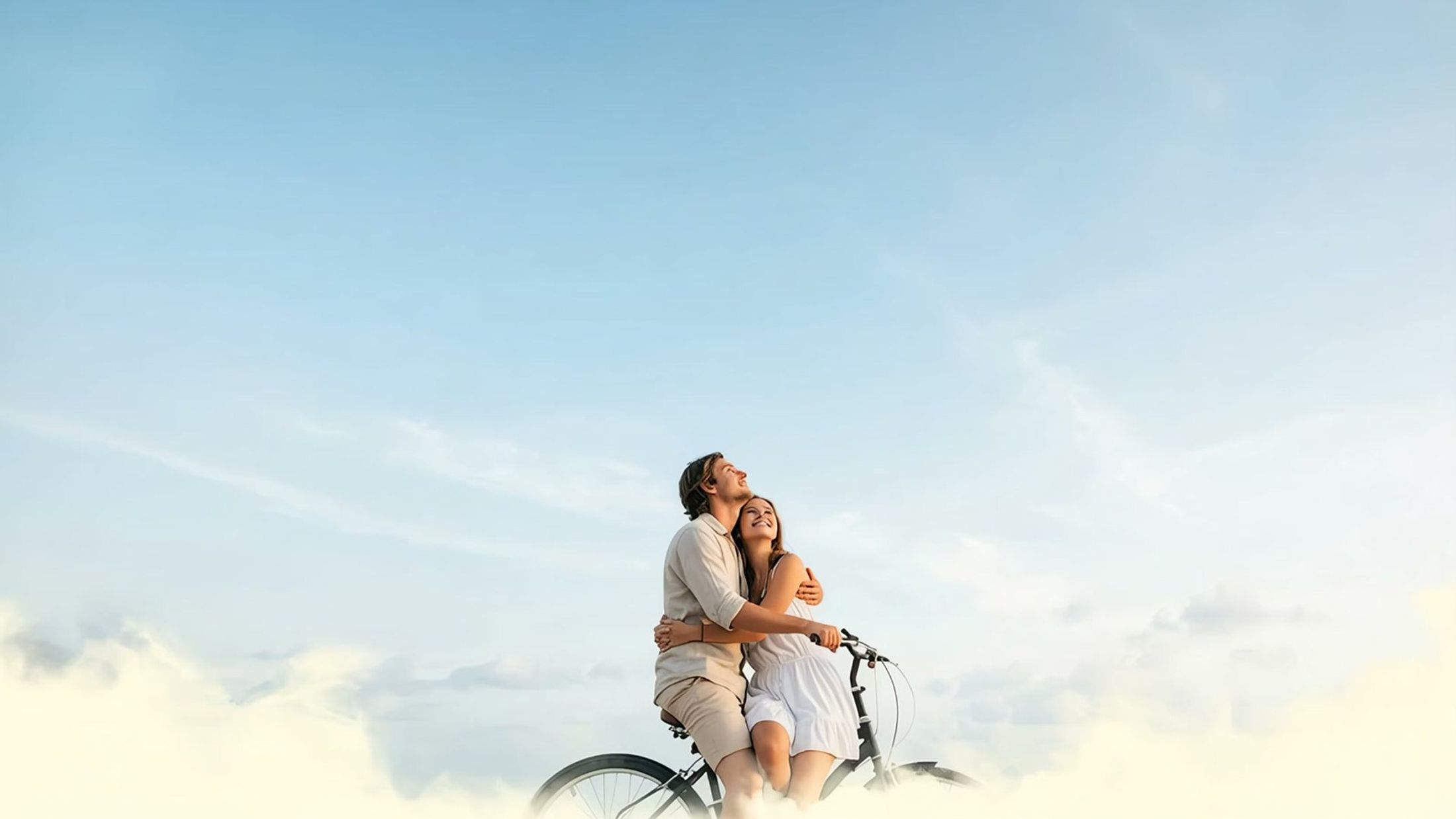 Couple on a bicycle against an open sky